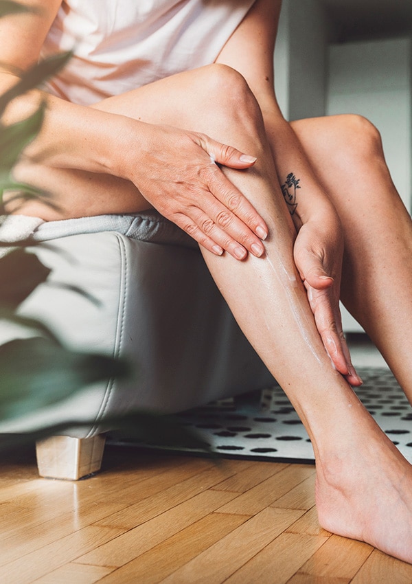 Mujer aplicando aceite de romero en las piernas