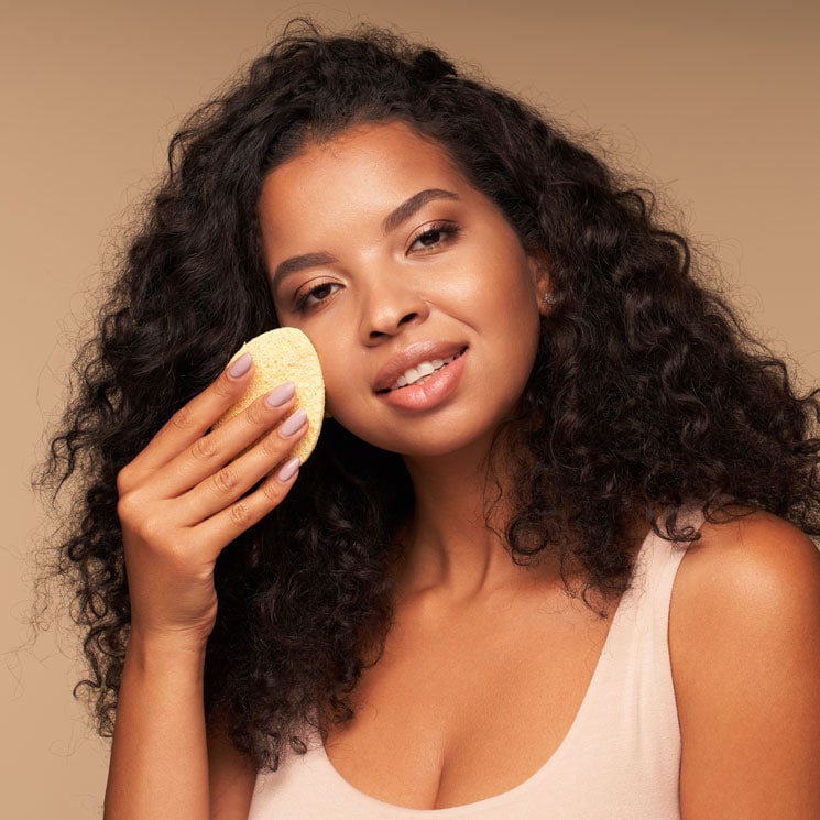 Mujer limpiando el rostro con una esponja