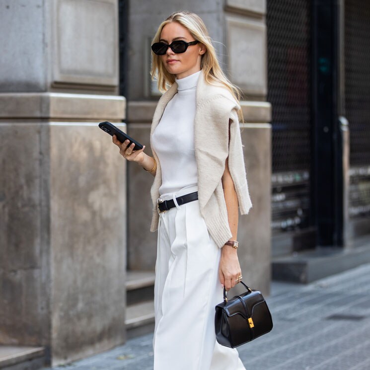 Claire Rose Cliteur con pantalones de traje, top blanco y jersey de punto