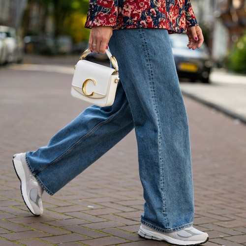 Mujer con vaqueros anchos, bolso blanco y zapatillas New Balance