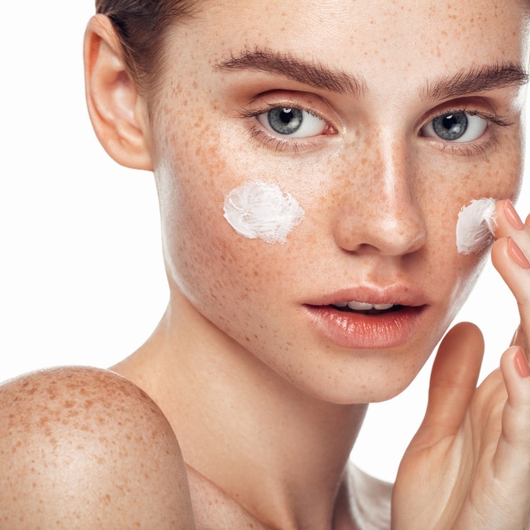 Modelo aplicándose crema en el rostro