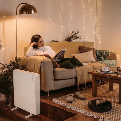 Mujer leyendo una revista en su sofá con radiador eléctrico