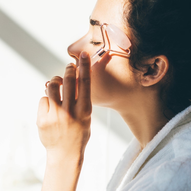 Mujer masajeando su rostro con un rodillo de cuarzo