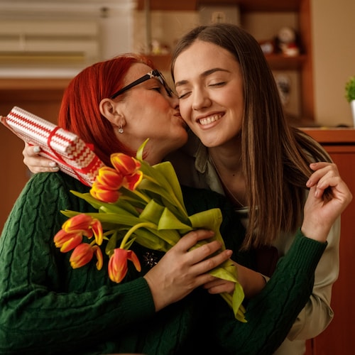 Hija entregando regalo y ramo de flores a su madre