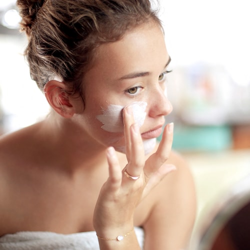 Mujer aplicando crema facial en el rostro