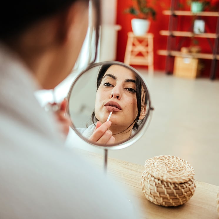 Mujer usando un espejo para maquillarse