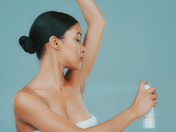 Mujer aplicándose desodorante en aerosol