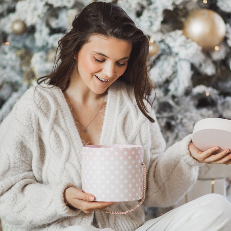 Mujer sorprendida abriendo un regalo de Navidad
