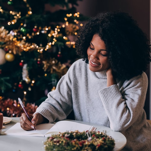 Mujer anotando cosas en un cuaderno en Navidad