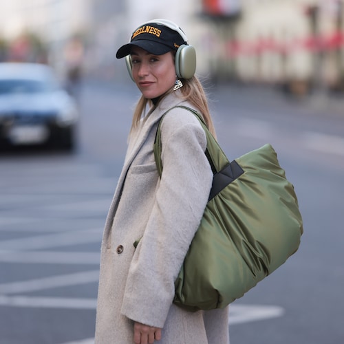 Sonia Lyson con abrigo beis, gorra, bolso shopper acolchado y cascos