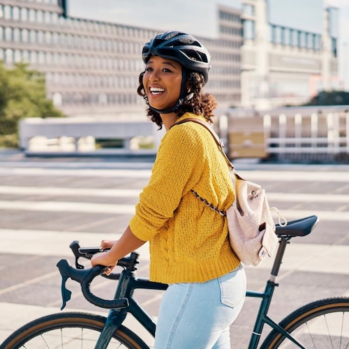 Mujer con bicicleta y casco por la ciudad