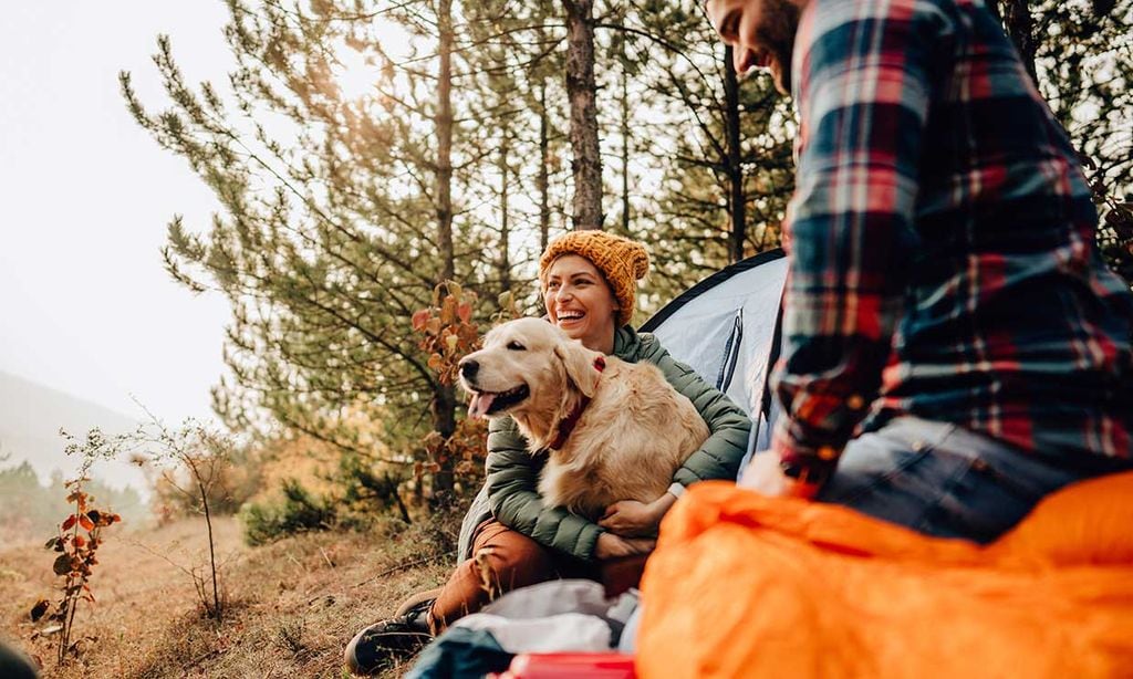 Una pareja de jóvenes con su perro haciendo acampada