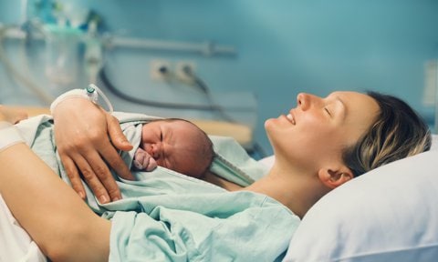 Mujer con su bebé recién nacido en brazos en el paritorio