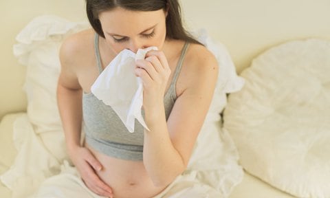 Mujer embarazada con un pañuelo por síntomas de alergia