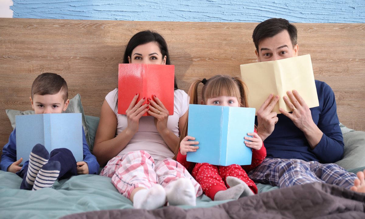 Familia leyendo cuentos en la cama.