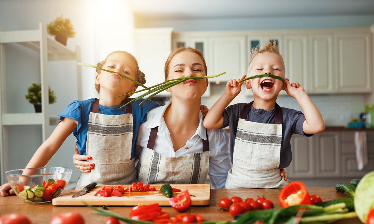 Madre con sus hijos en la cocina en actitud divertida