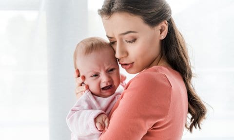 Bebé pequeño llorando en brazos de su madre