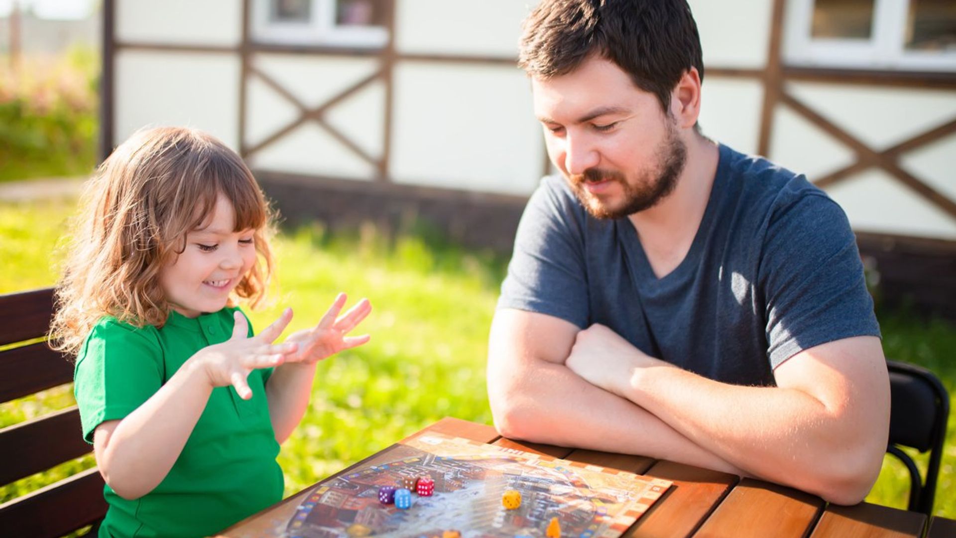 Padre jugando con su hija a juego de mesa en el jardín.