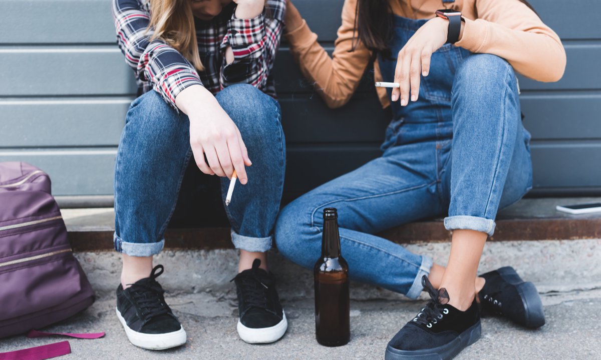 Adolescentes bebiendo alcohol y fumando tabaco.