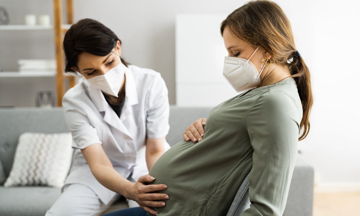 Mujer embarazada en el médico con mascarilla