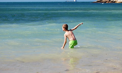 Niño bañándose en la playa en verano.