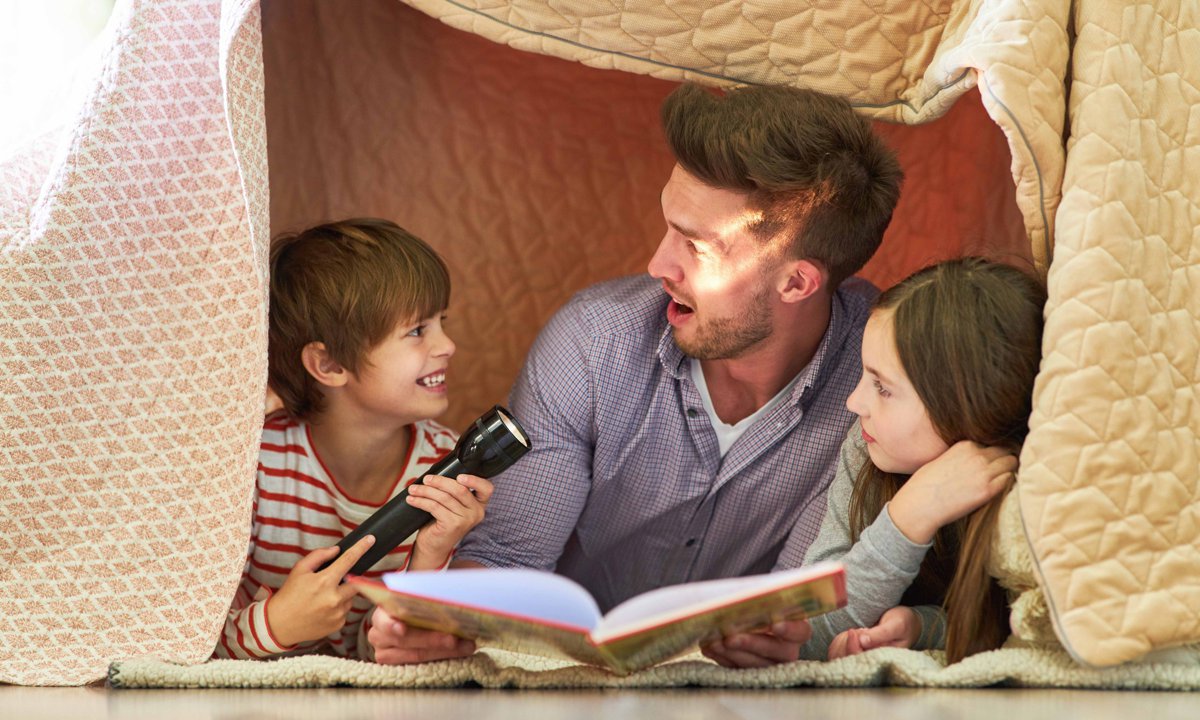 Padre con sus hijos leyendo un cuento en el suelo