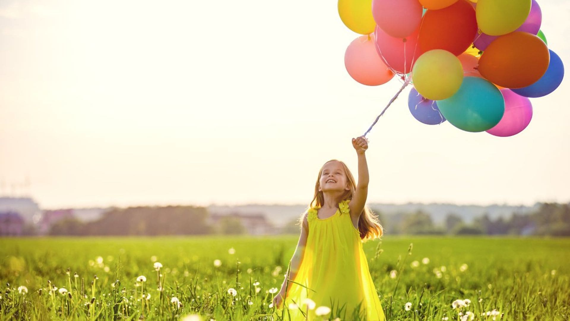 Niña en el campo con globos en la mano