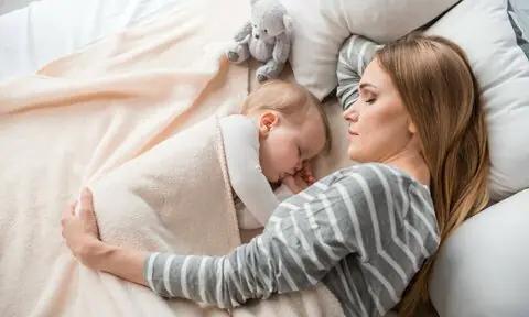 Madre durmiendo con su bebé en la cama. Colecho.