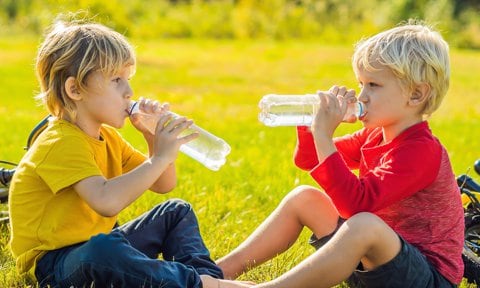 Niños bebiendo agua en el parque en verano.