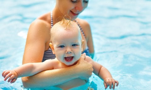 Bebé dándose un baño en la piscina o playa. Estimular movimientos en agua.