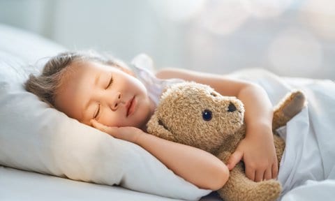 Niña durmiendo con un oso de peluche