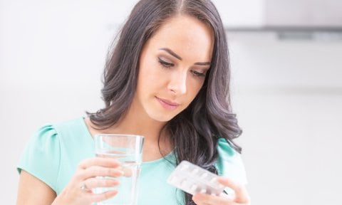 Mujer tomando una pastilla de ácido fólico