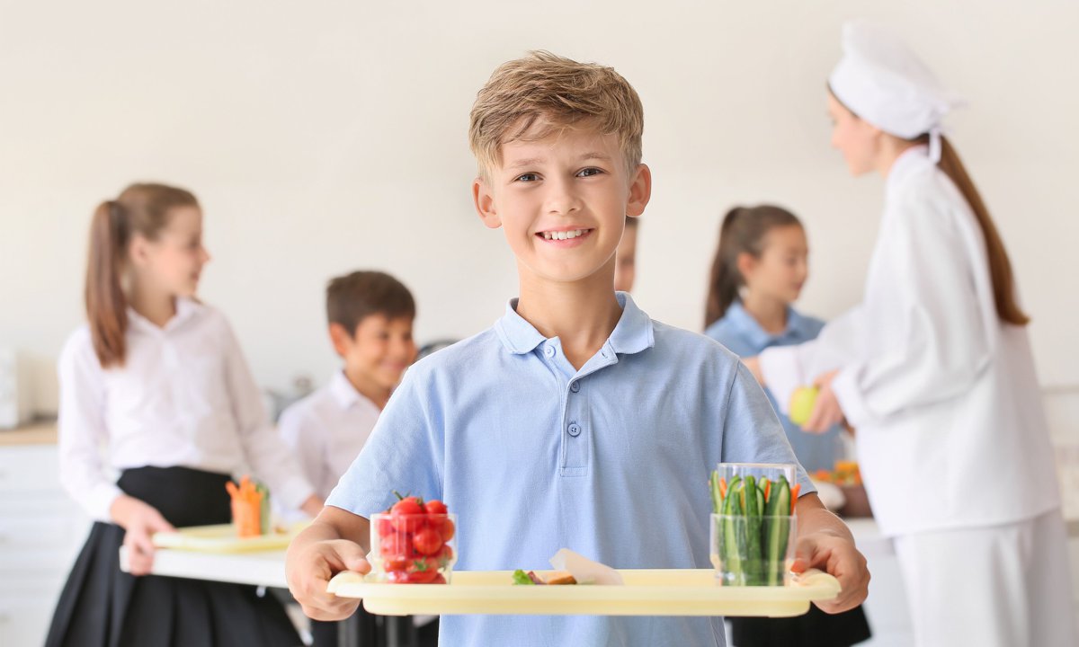 Niño llevando una bandeja en el comedor del colegio