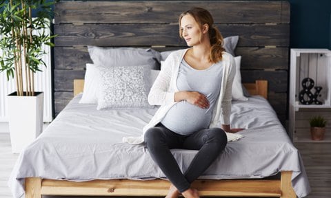 Embarazada sentada en la cama con ansiedad