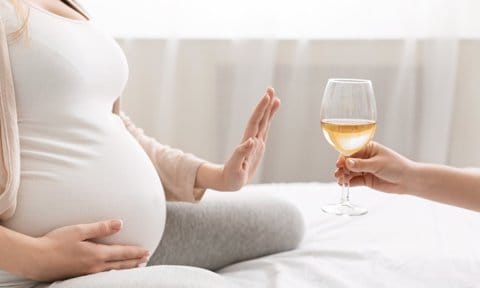 Mujer embarazada rechazando copa de alcohol