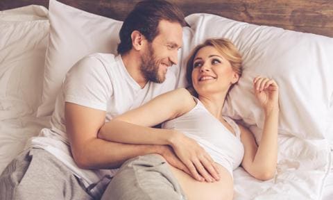 Embarazada y su pareja en la cama
