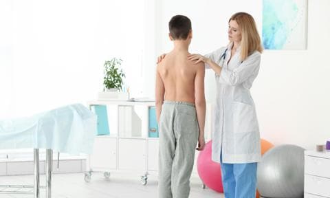 Médico examinando la escoliosis de un niño