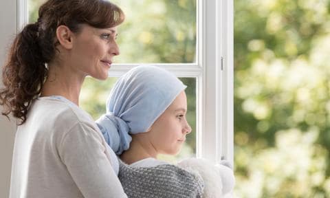 Madre con su hija enferma de cáncer mirando por la ventana