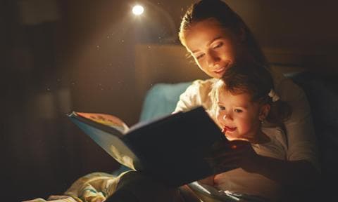 Madre e hija leyendo un cuento en la cama de noche