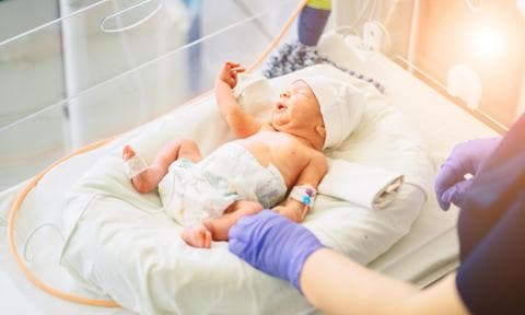 Bebé prematuro en la cuna atendido por una enfermera