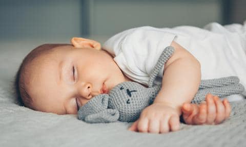 Bebé durmiendo con muñeco de apego