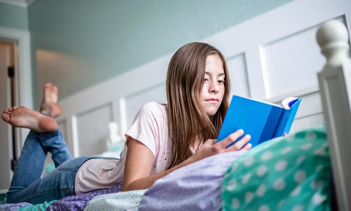 Adolescente leyendo en su cama