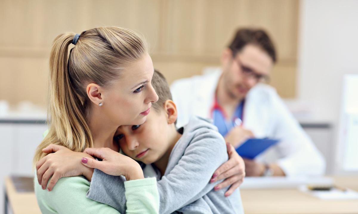 Niño abrazado a su madre en la consulta del pediatra