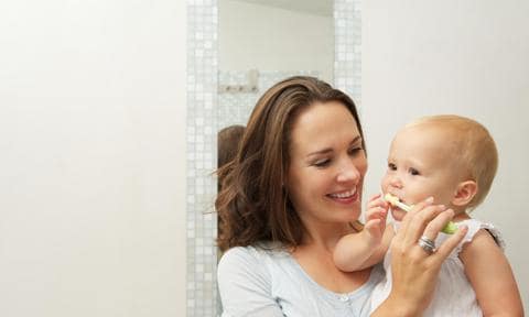 Mamá cepillando los dientes a su bebé