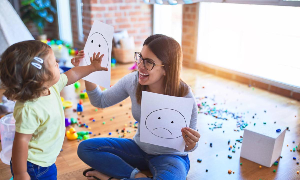 Educadora enseñando dibujos con emociones a niña