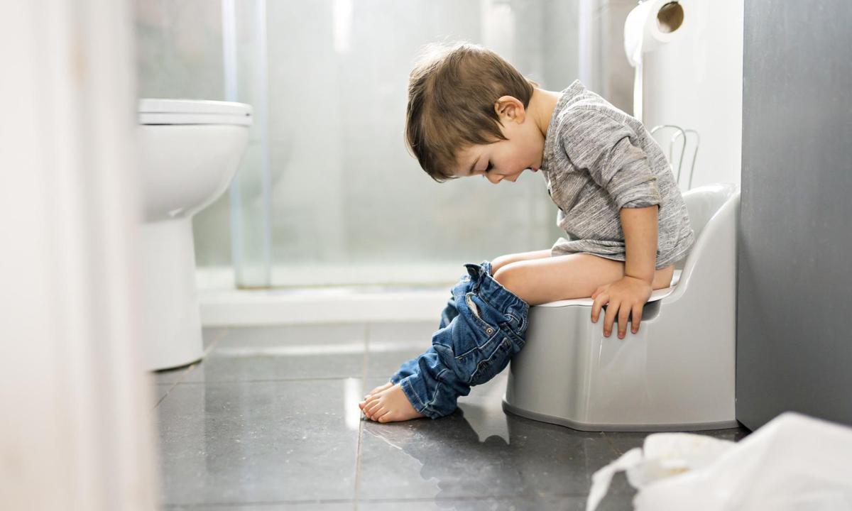 Encopresis infantil. Niño sentado en el WC portátil.