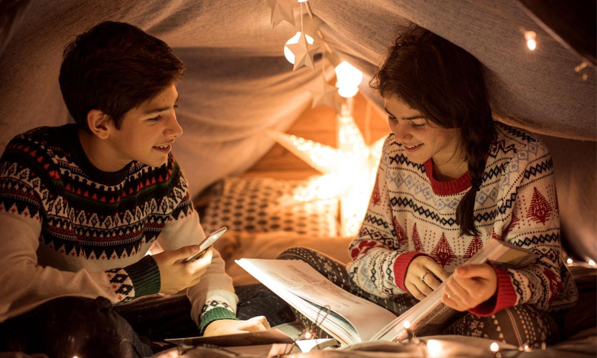 Adolescentes leyendo libro por Navidad.