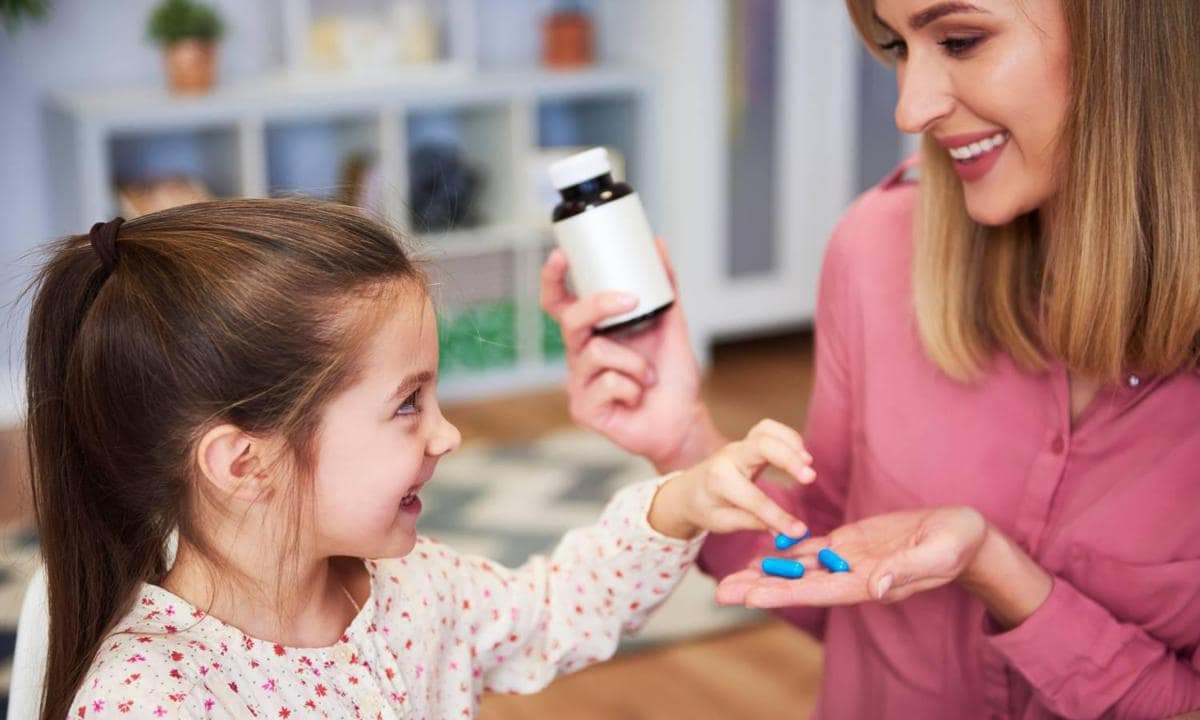 Mamá con medicamentos en la mano para su hija