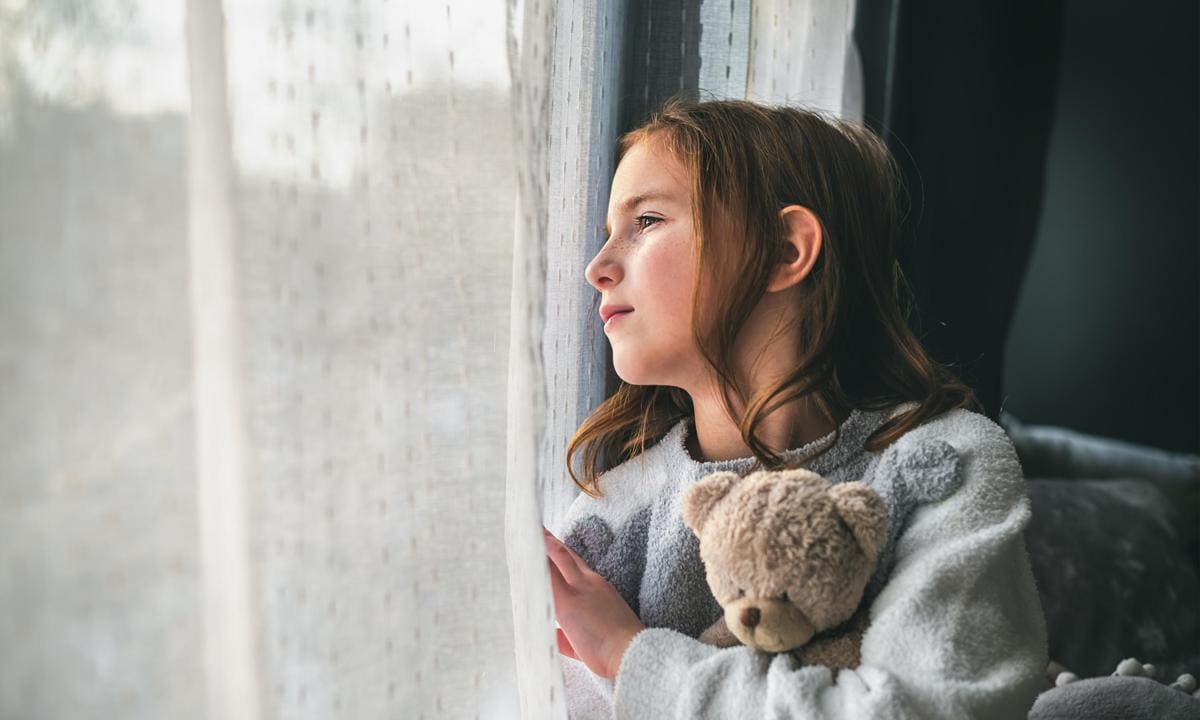 Niña asomada a una ventana pensativa