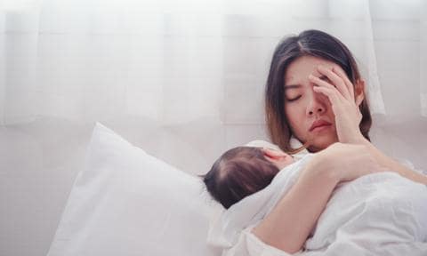 Mujer cansada con su bebé recién nacido en brazos